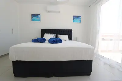 a bedroom with a bed with two blue pillows on it at Nissi 3 Amazing Sea View Apartment in Ayia Napa