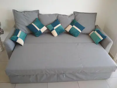 a grey couch with blue and white pillows on it at Nissi 3 Amazing Sea View Apartment in Ayia Napa