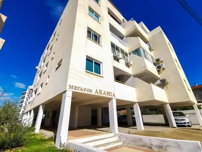 a large white building with a sign on it at Sun Kissed Apartment in Larnaka
