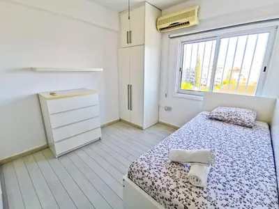 a small bedroom with a bed and a window at Sun Kissed Apartment in Larnaka