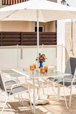a white table and chairs with an umbrella at Villa Rosedale by Ezoria Villas in Ayia Napa