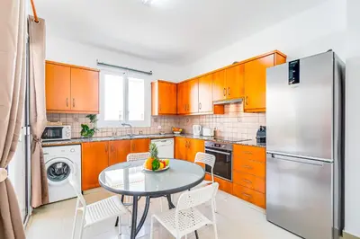 a kitchen with a table and a stainless steel refrigerator at Villa Rosedale by Ezoria Villas in Ayia Napa