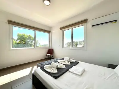 a bedroom with a large bed with two windows at STAY Symphony Apartment in Protaras