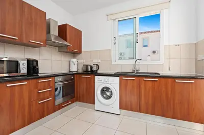 a kitchen with wooden cabinets and a washer and dryer at Villa millie Cyprus in Protaras