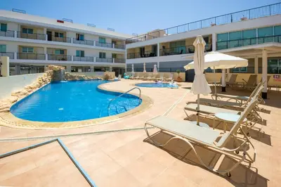 a swimming pool with lounge chairs and a hotel at SEABREEZE APARTMENT 200m away from the sea in Paralimni