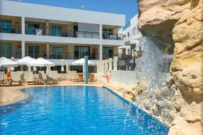 a swimming pool with a waterfall in front of a hotel at SEABREEZE APARTMENT 200m away from the sea in Paralimni