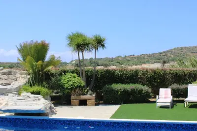 a pool with two lawn chairs and palm trees at Immaculate 3-Bed House in Pentakomo in Pendakomo