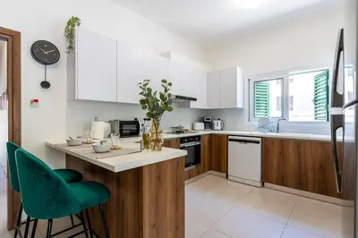 a kitchen with white cabinets and a green chair at Arty Haven - Spacious 3-BR House in Larnaca in Larnaka