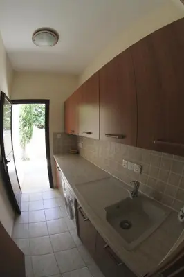 a kitchen with a sink and wooden cabinets at Eve Pissouri Soultanina Villa in Pissouri