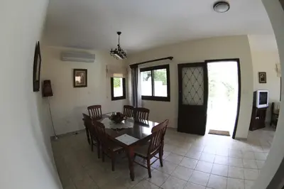 a dining room and living room with a table and chairs at Eve Pissouri Soultanina Villa in Pissouri