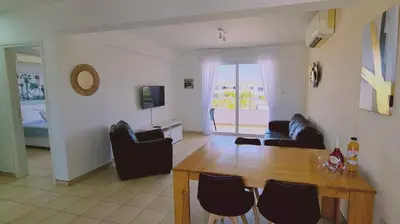 a living room with a wooden table and chairs at Nissi 3 Privileges Apt in Ayia Napa