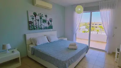 a bedroom with a bed and a view of a balcony at Nissi 3 Privileges Apt in Ayia Napa