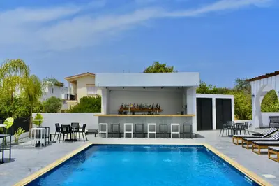 a swimming pool with tables and chairs next to a house at Zoi Ayia Napa in Ayia Napa