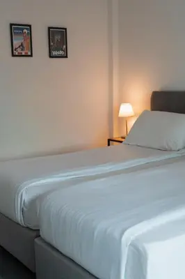 a white bed in a room with two pictures on the wall at Zoi Ayia Napa in Ayia Napa