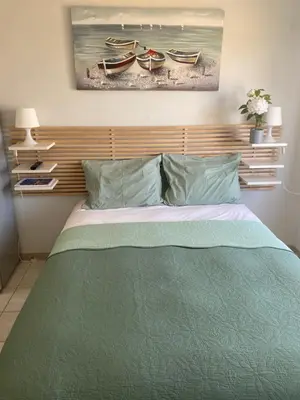 a bed with a green comforter and two boats at Dene Hollow Ayia Napa in Ayia Napa