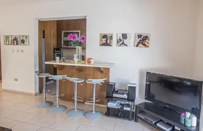 a living room with a bar with stools and a television at Artemisia Villa in Protaras