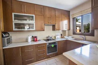 a large kitchen with wooden cabinets and a window at Artemisia Villa in Protaras
