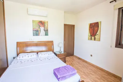 a bedroom with a large white bed and paintings on the wall at Artemisia Villa in Protaras