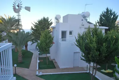 a white house with trees in front of it at Flisvos Beach Apartments in Protaras