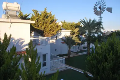 a view of a white house with a windmill at Flisvos Beach Apartments in Protaras