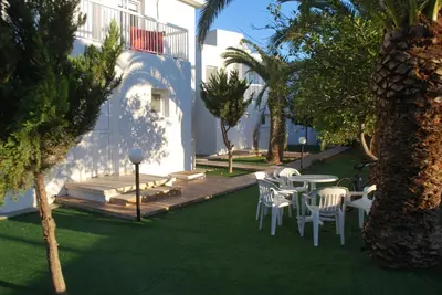 a patio with a table and chairs and palm trees at Flisvos Beach Apartments in Protaras