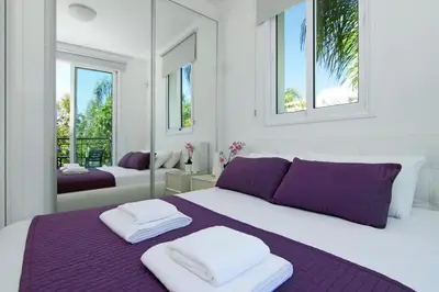 a white bedroom with a purple bed with mirrors at Villa Blue Oasis in Protaras