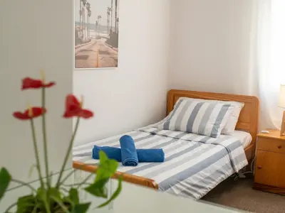 a small bedroom with a bed with blue slippers at The Salnik Beach Apartment in Limassol