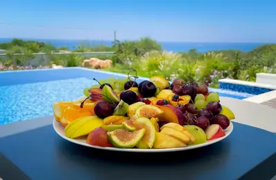 a plate of fruit on a table next to a pool at Love Bridge Seaview Villas in Ayia Napa