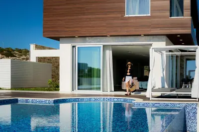 a woman standing outside of a house next to a swimming pool at Love Bridge Seaview Villas in Ayia Napa