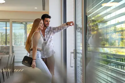 a man and a woman standing in front of a window at Mythical Villas Zeus and Venus in Protaras