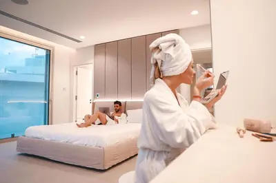a woman in a bathrobe with a towel on her head sitting on a bed at Mythical Villas Zeus and Venus in Protaras