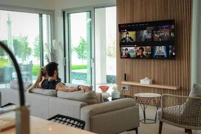 a woman sitting on a couch watching tv in a living room at Mythical Villas Zeus and Venus in Protaras