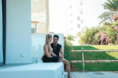 a man and a woman sitting next to a bed at Mythical Villas Zeus and Venus in Protaras