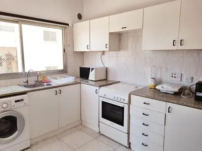 a kitchen with white cabinets and a washer and dryer at Ikaros Boutique Apartment in Limassol