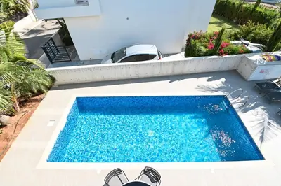 a swimming pool with shoes next to a house at By the Beach Villa 12 in Protaras