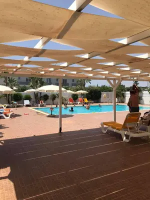 a pool with chairs and umbrellas and a person taking a picture at Mythical Sands Resort Ilona Apartment for families in Protaras