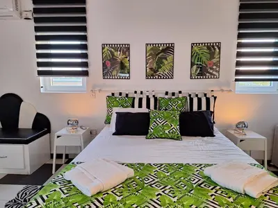 a bedroom with a large bed with green pillows at The Pervoli Studio - Pool - Close to Beach in Larnaka