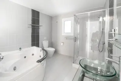 a bathroom with a tub and a shower and a toilet at Villa Amelia by Ezoria Villas in Pervolia