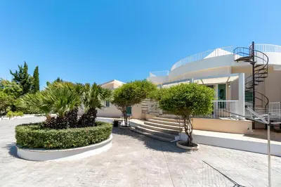 a building with palm trees in front of it at Villa Amelia by Ezoria Villas in Pervolia