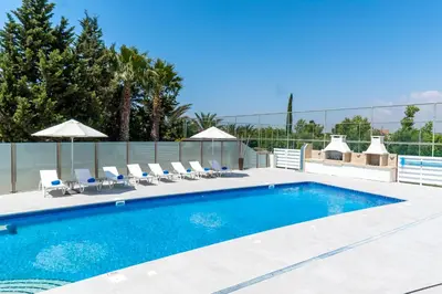 a large swimming pool with chairs and umbrellas at Villa Amelia by Ezoria Villas in Pervolia