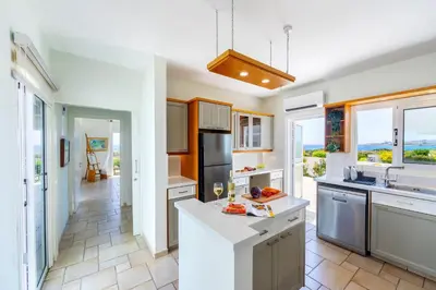 a kitchen with white countertops and a large window at Protaras Seafront Villa Violetta in Protaras