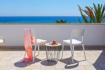 two chairs and a table on a patio with the ocean at Protaras Seafront Villa Violetta in Protaras