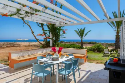 a patio with a table and chairs under a pergola at Protaras Seafront Villa Violetta in Protaras