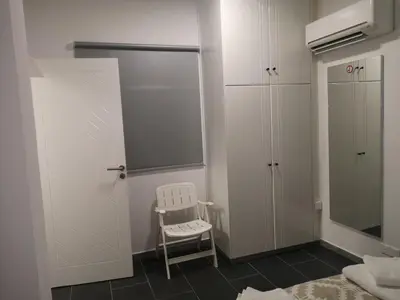 a bedroom with white cabinets and a white chair at Kalidonia “PANORAMA” STUDIO APARTMENT in Engomi