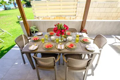 a table with food and flowers on a patio at Pebble Beach Apartment in Voroklini