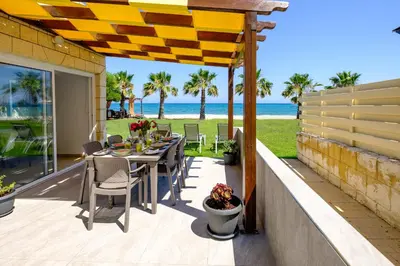 a patio with a table and chairs and the ocean at Pebble Beach Apartment in Voroklini