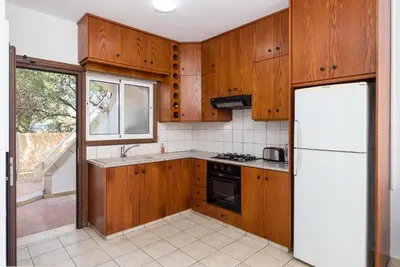 a kitchen with wooden cabinets and a white refrigerator at Pebble Beach Apartment in Voroklini
