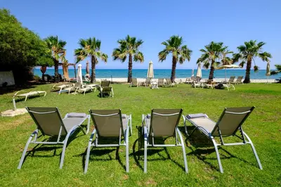 a group of lawn chairs and umbrellas on the beach at Oceanview Apartment in Larnaka