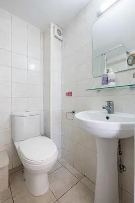a white bathroom with a toilet and a sink at Oceanview Apartment in Larnaka