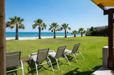 a group of chairs sitting on the grass near the beach at Oceanview Apartment in Larnaka